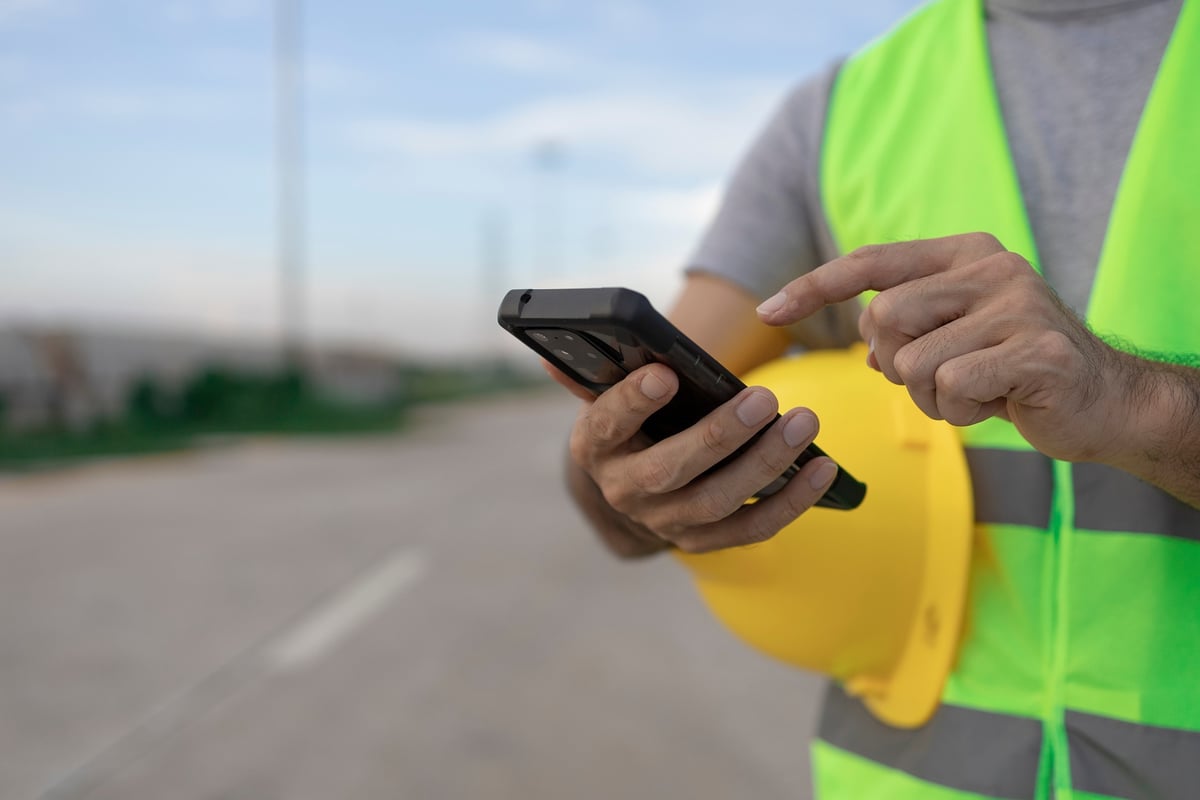 Arbeiter setzt Smartphone im Außendienst zur Datenerfassung ein