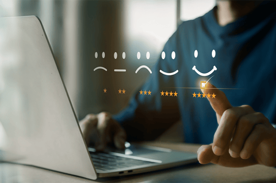 Person sitzt vor einem Laptop mit Icons, die die Zufriedenheit wiederspiegeln