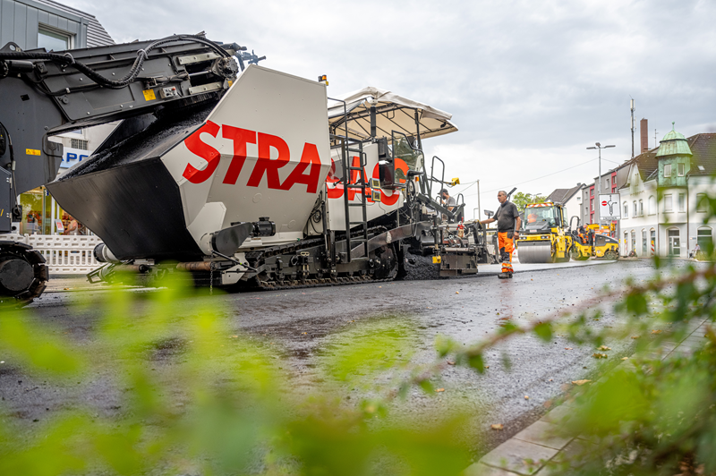 Aspahltierungsarbeiten mit Baustellen-Fahrzeugen und einem STRABAG Mitarbeiter