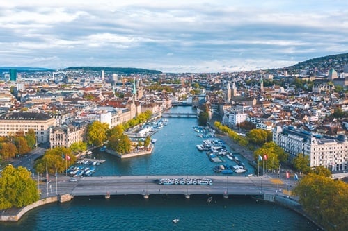 Luftaufnahme der Zürcher Innenstadt mit der Limmat, mehreren Brücken, Uferanlagen und dicht bebauten Stadtquartieren.