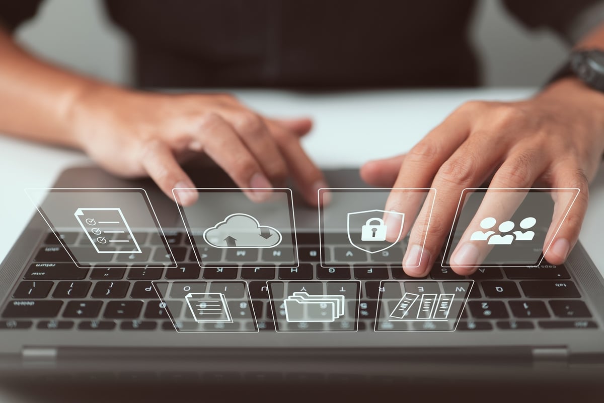 Person arbeitet am Laptop mit Symbolen die für Datenmanagement stehen