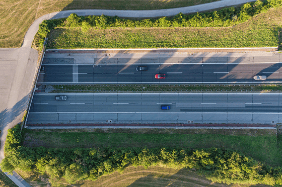 Luftaufnahme einer mehrspurigen Bundesstraße mit Fahrzeugverkehr, eingebettet in eine grüne Landschaft
