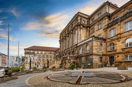 Historisches Hauptgebäude der Universität Kassel mit klassischer Sandsteinfassade und Platz im Vordergrund.