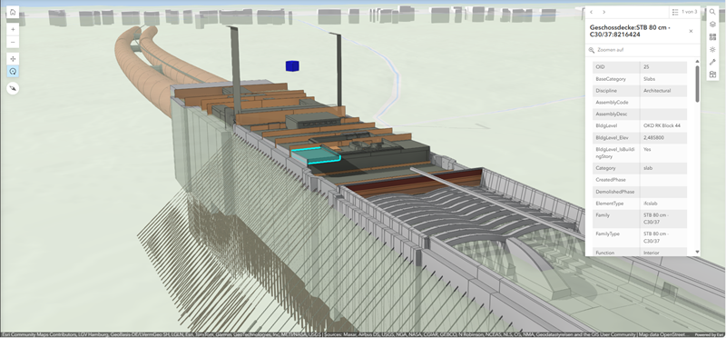 3D-Modell eines technischen Bauwerks, sichtbar in einer CAD-/BIM-Software. Dargestellt ist eine längliche, rechteckige Struktur mit mehreren Ebenen und Bauteilen auf der Oberseite, darunter rechteckige Kästen in verschiedenen Größen sowie hervorgehobene Elemente in Türkis und Dunkelgrau. Auf der linken Seite schließen zwei große, gebogene Rohrleitungen an das Bauwerk an. Entlang der Seiten verlaufen vertikale Stützen oder Pfähle, die dicht aneinandergereiht nach unten reichen. Im vorderen Bereich ist eine gewölbte, tunnelartige Struktur mit parallelen Streben zu sehen.