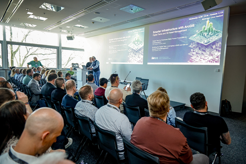 Teilnehmende verfolgen eine Präsentation zu GIS und digitalem Infrastrukturmanagement auf einer internationalen Fachkonferenz. 