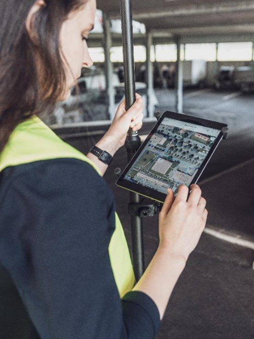 Frau mit Messgerät arbeitet an einem Tablet mit ArcGIS FieldMaps